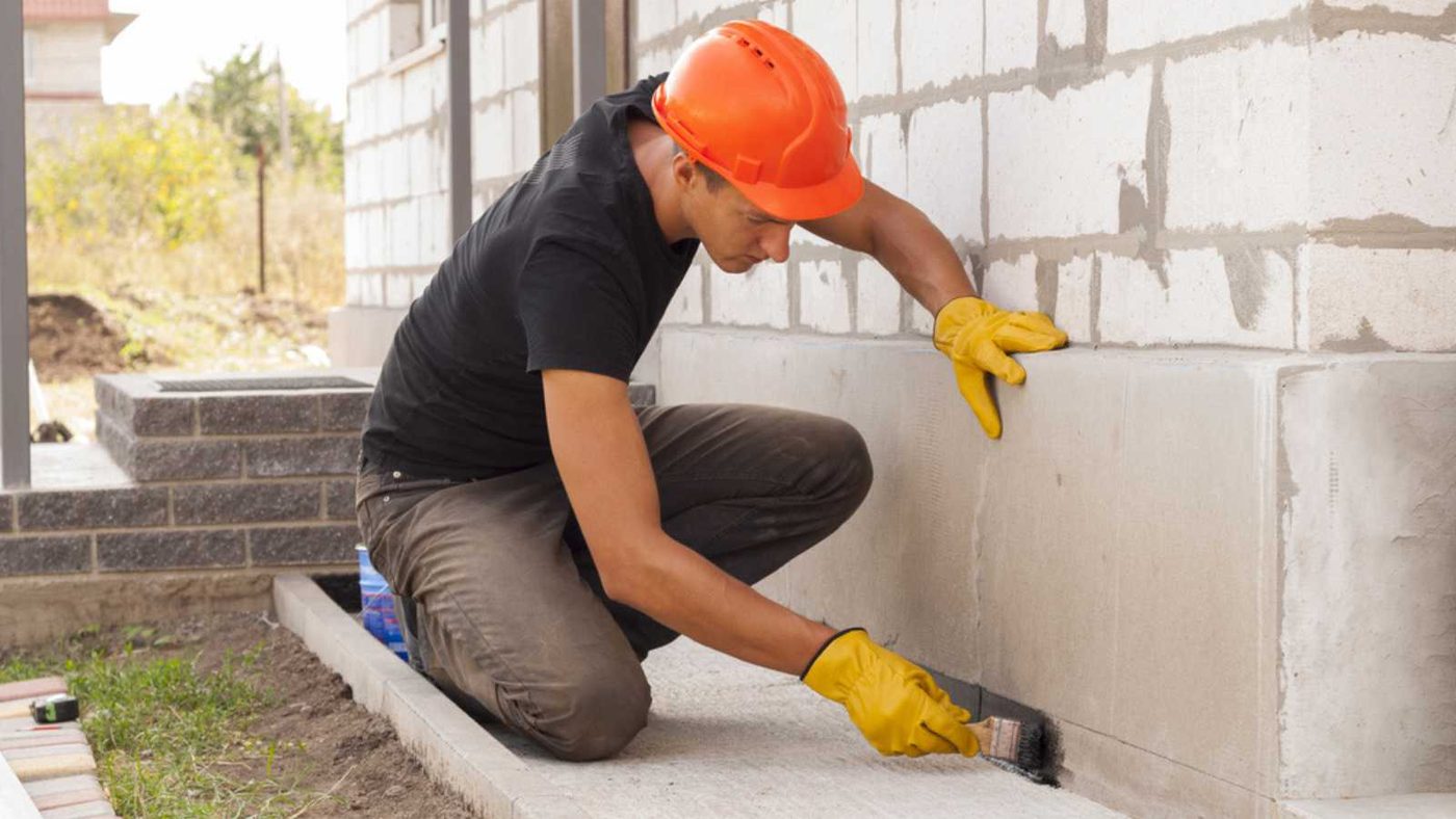 worker applies bitumen mastic on the foundation
