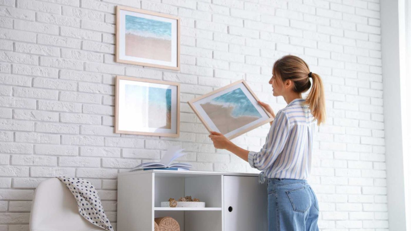 Woman Hanging Photos On Wall