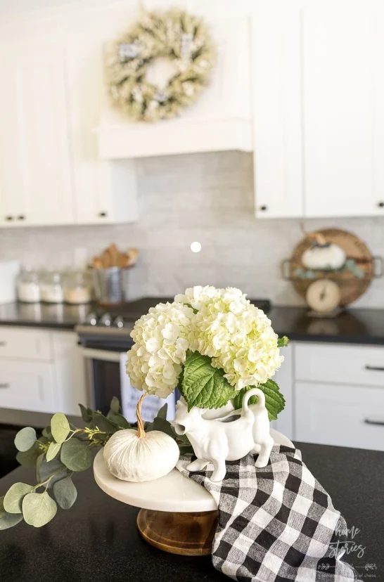 White Cupboards, Off White Backsplash, Black Countertops, White Flowers With Green Leaves