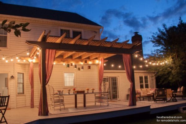 Pergola With Hanging String Lights Curtains And Dinner Table Shown At Night