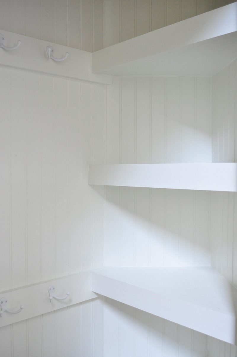 hall closet organized with floating corner shelves and hooks