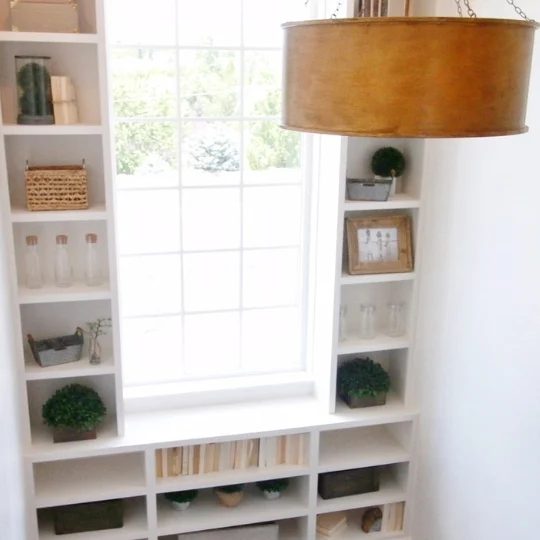 Window Lined With Built In White Shelves With Books And Plants And Vases