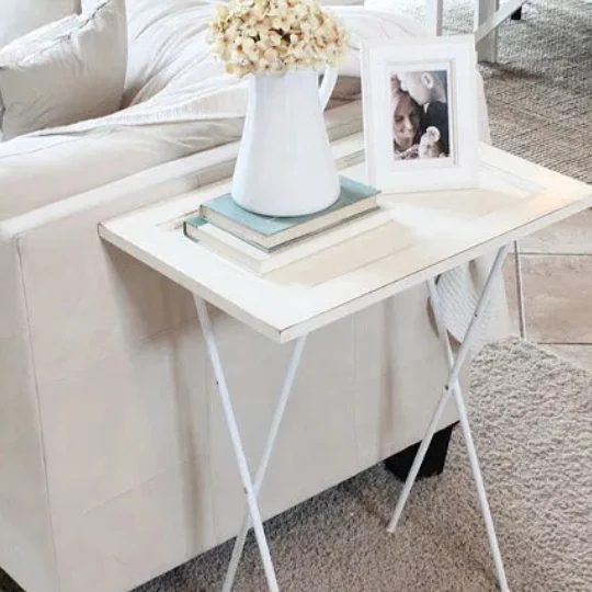 White Couch With White End Table, Books, Framed Photo And Flowers In White Pitcher