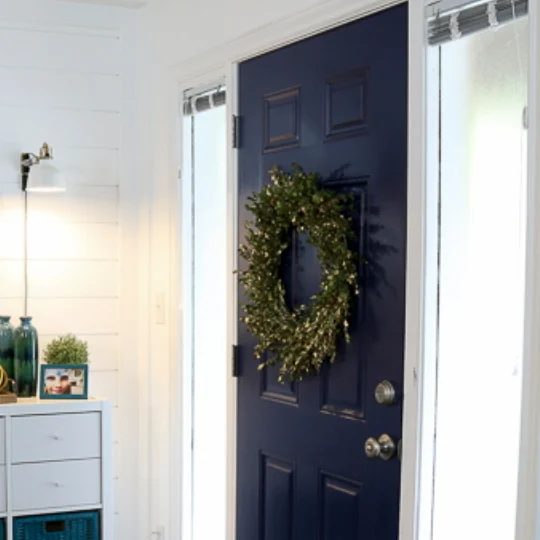 White Walls With striking Blue Door And Green Wreath