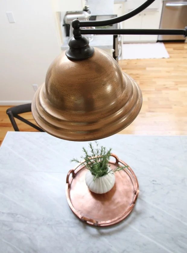 This faux copper painted light is so vivid in this white and marble kitchen!