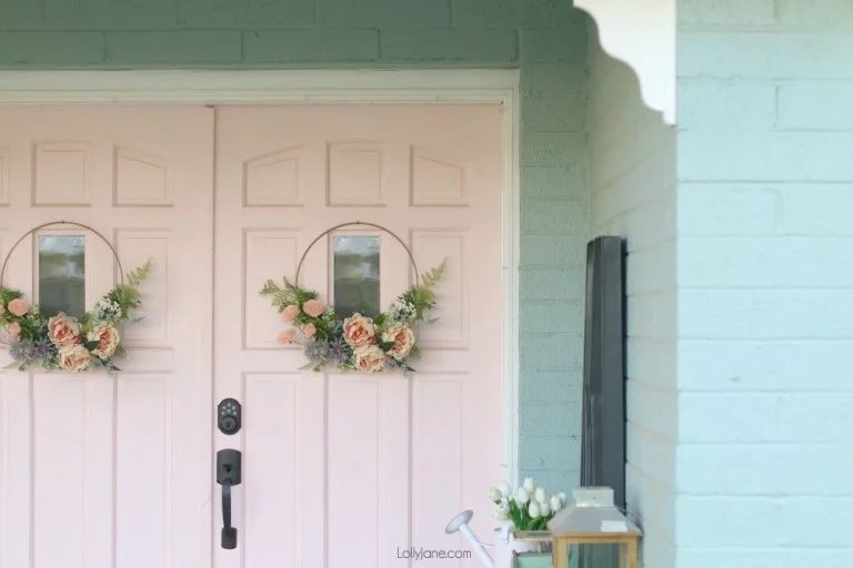 White Double Doors With striking Pink Floral Wreaths On A Light Blue House