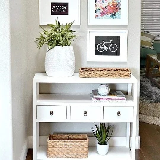 White Dresser With Three Small Drawers And Three Shelves With Wicker Baskets And Greenery