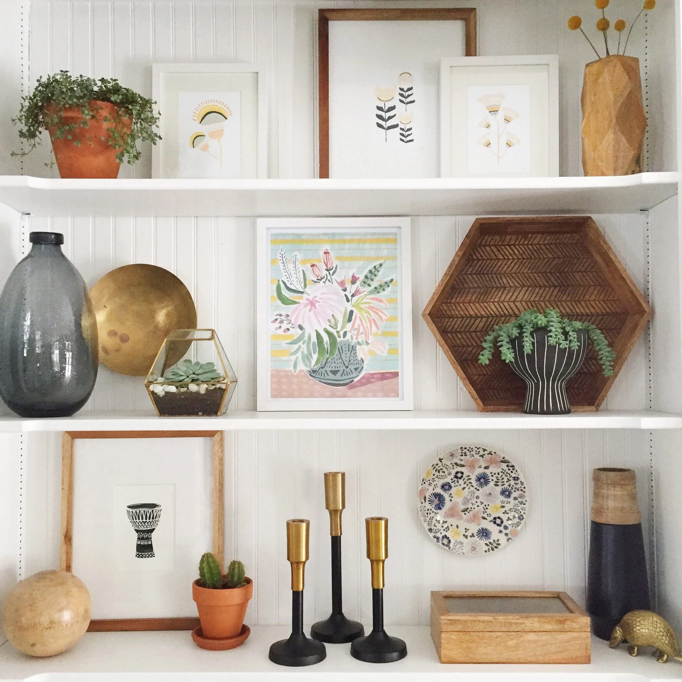 These shelves are well fitted. Pretty art, and love that hexagon tray and all the wood and gold tones.
