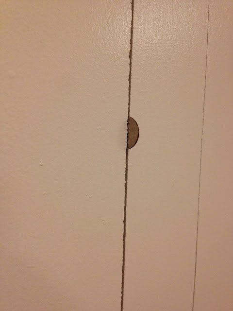 use quarters to evenly space planks for barn door inspired wall treatment