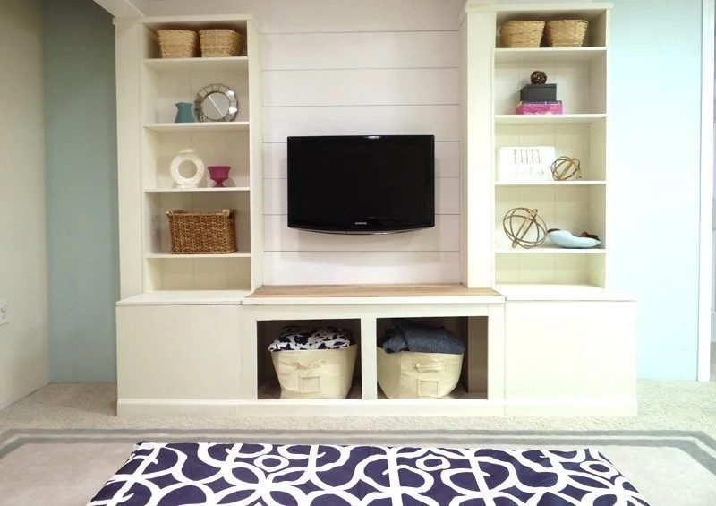 Built In White Shelves And Media Wall Unit With Storage Squares Against Blue Wall With Blue Rug