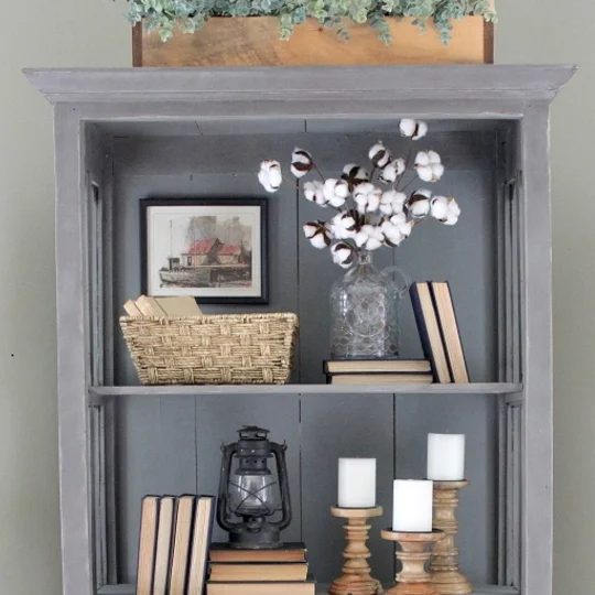 Grey Cabinet With Wood Accents, Books, White Candles And Basket