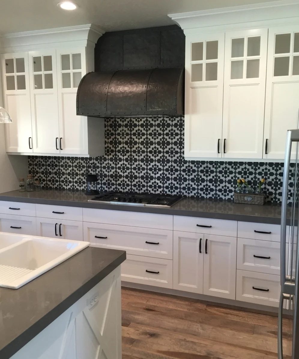 White Cupboards, Black Handles, Black And White Tiled Backplash And Metal Stove Hood