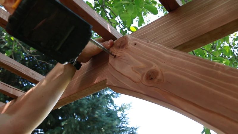 attaching a curved cross-piece to the backyard wedding garden arbor