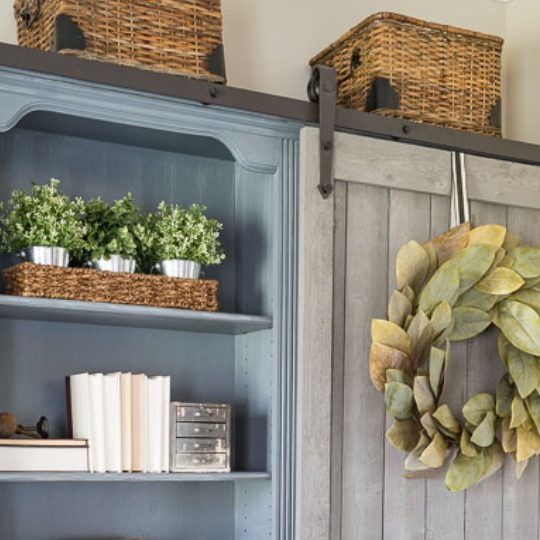 Sliding Door Bookcase With Leaf Wreath And Blue Shelves