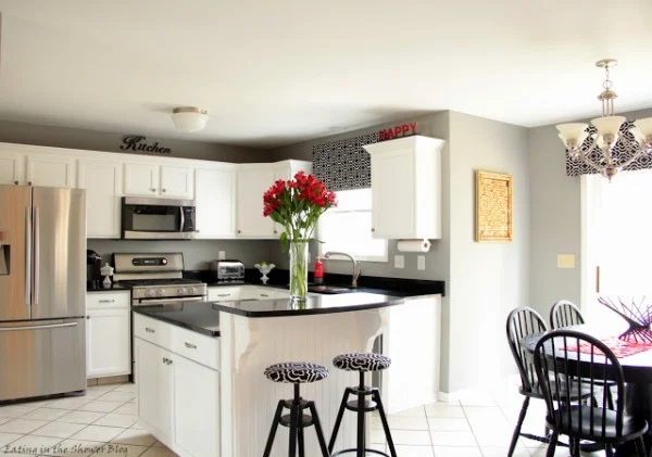 Black And White Kithen With White Cupboards And Black Countertops And Wallpaper