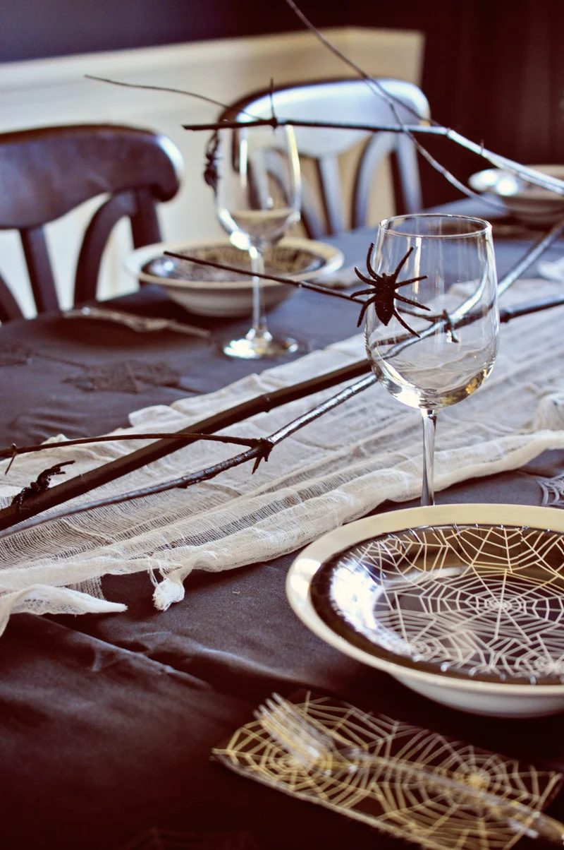 straightforward Halloween table setting, using spray painted branches and cheesecloth as a runner | direct Halloween Decor options and Tutorials at Bekob.com
