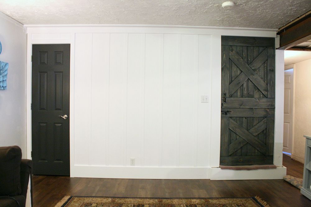 interior door in Iron Ore, with a real wood dutch barn door colorwashed and stained to match, along a tall white board and batten wall (Bekob)