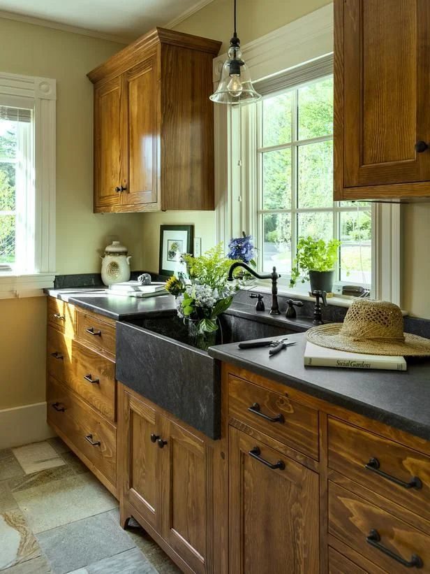 striking kitchenw ith wood cabinets and black countertops and apron sink (via HGTV)