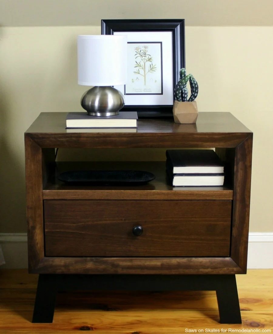 This chunky wood nightstand is made from solid wood and features angled mid-century style legs, an open shelf, and a sliding drawer for storage. Free building plan and walkthrough.