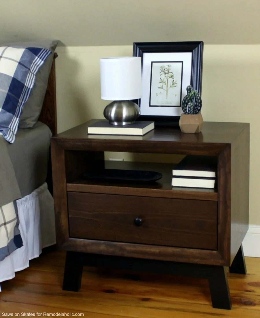 This chunky wood nightstand is made from solid wood and features angled mid-century style legs, an open shelf, and a sliding drawer for storage. Free building plan and walkthrough.