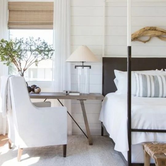 Farmhouse Bedroom With White Walls, White Bedding, White Chair, Accents Of Brown