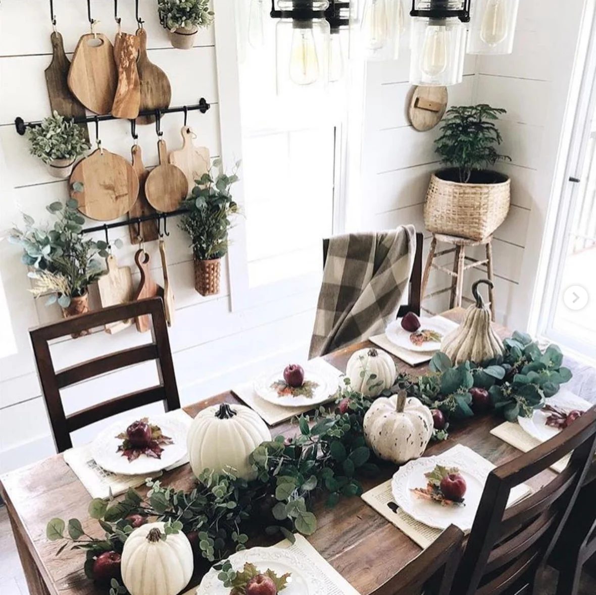 Wood Dining Table With Fall Tablescape; Greenery, White Pumpkins, And Apples On Each Plate