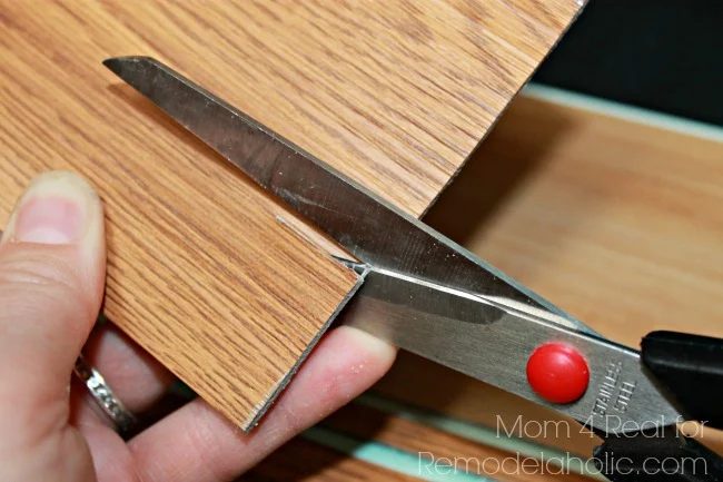 Use straightforward to cut vinyl flooring to make a peel and stick plank backsplash in your kitchen