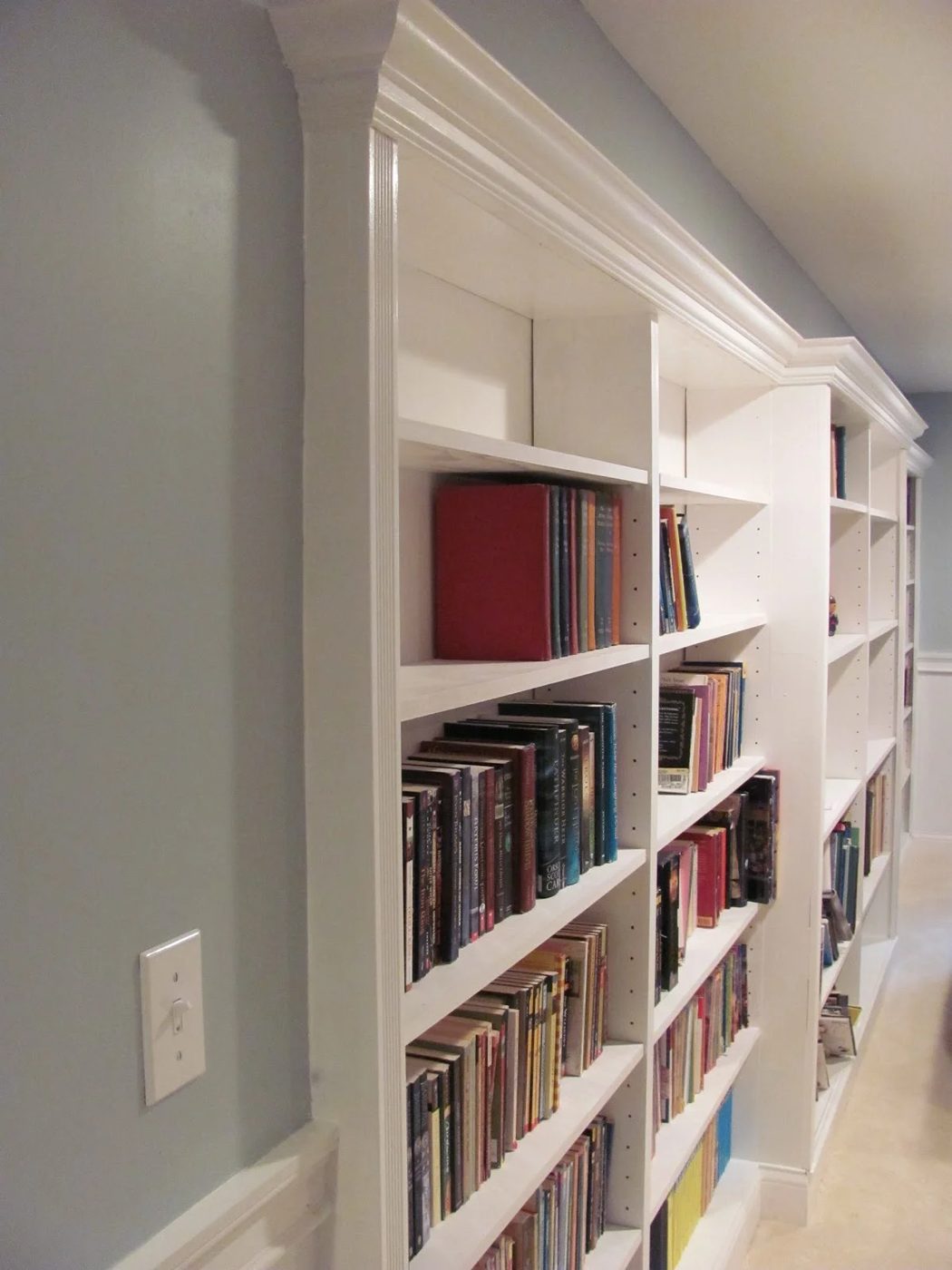 basement rec room with recessed built-in bookshelf under a soffit