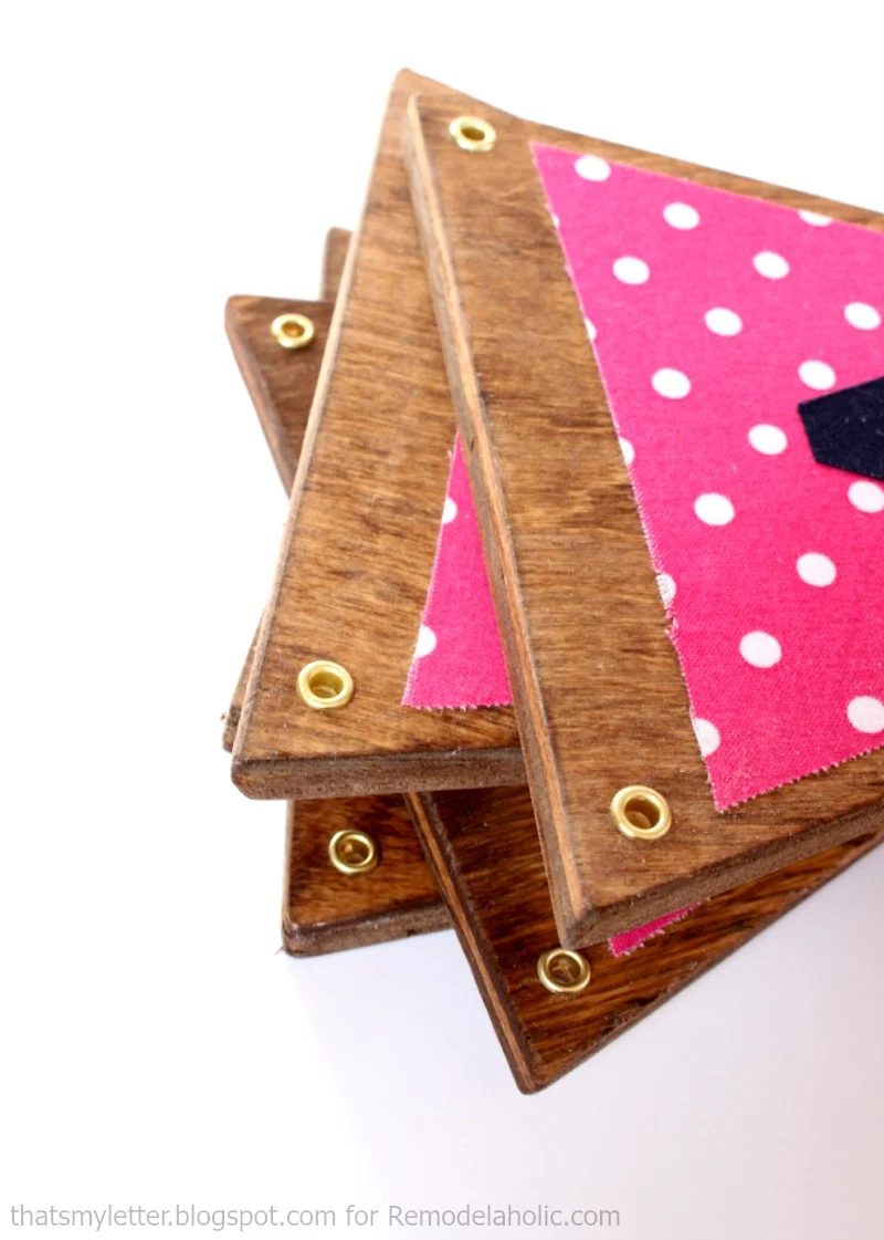 use metal grommets on triangles of scrap wood to make a cute fabric and wood bunting