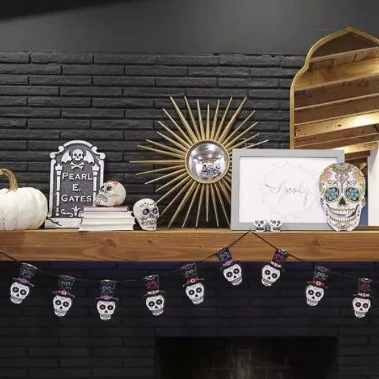 Black Brick Fireplace With Light Brown Stained Shelf With Skull Decor And Garland