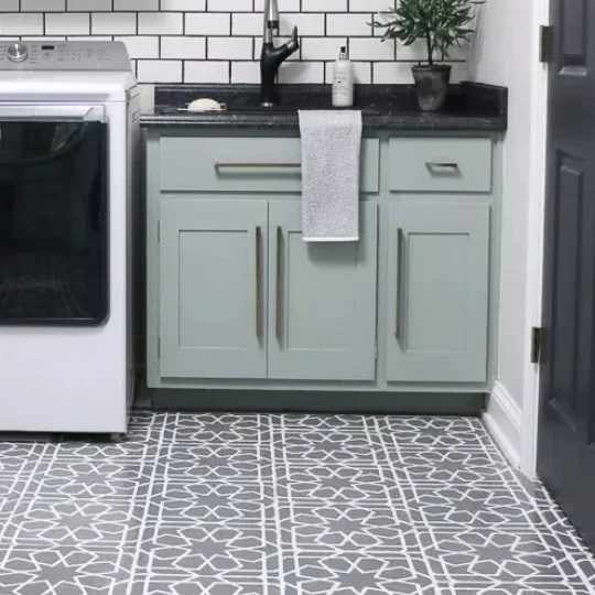 Grey Patterned Tile Floor With Mint Green Cabinets, Black Countertop And White Brick Wall
