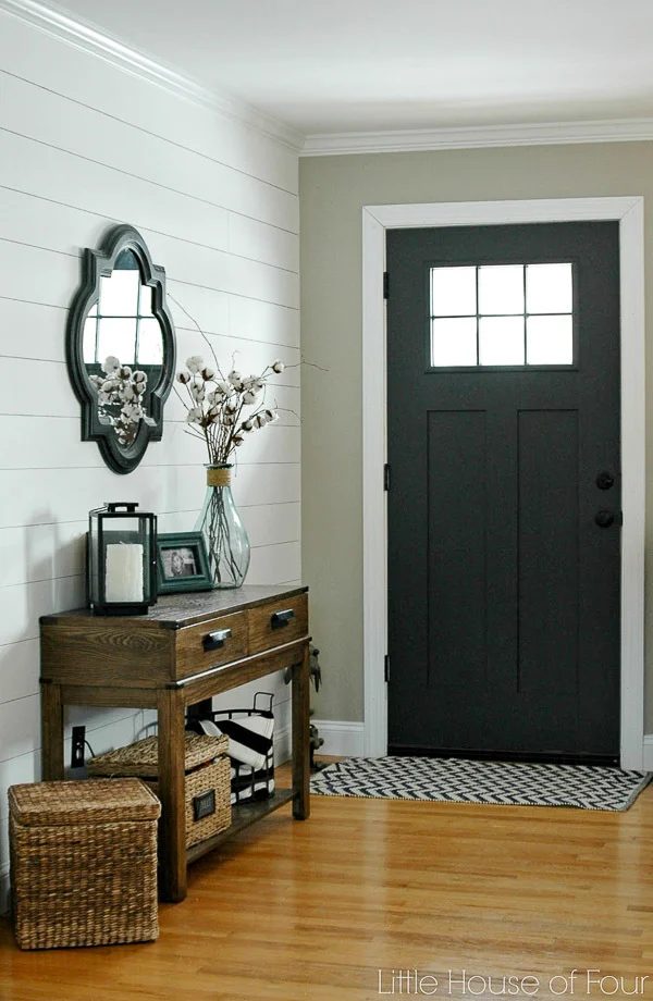 Entryway With White Shiplap Accent Wall, Wooden Long Table, Black Front Door, Accent Rug And Wood Floor