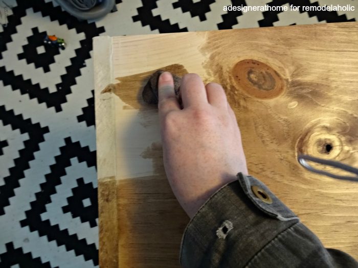 apply stain to wood using an old rag, wiping in the direction of the grain