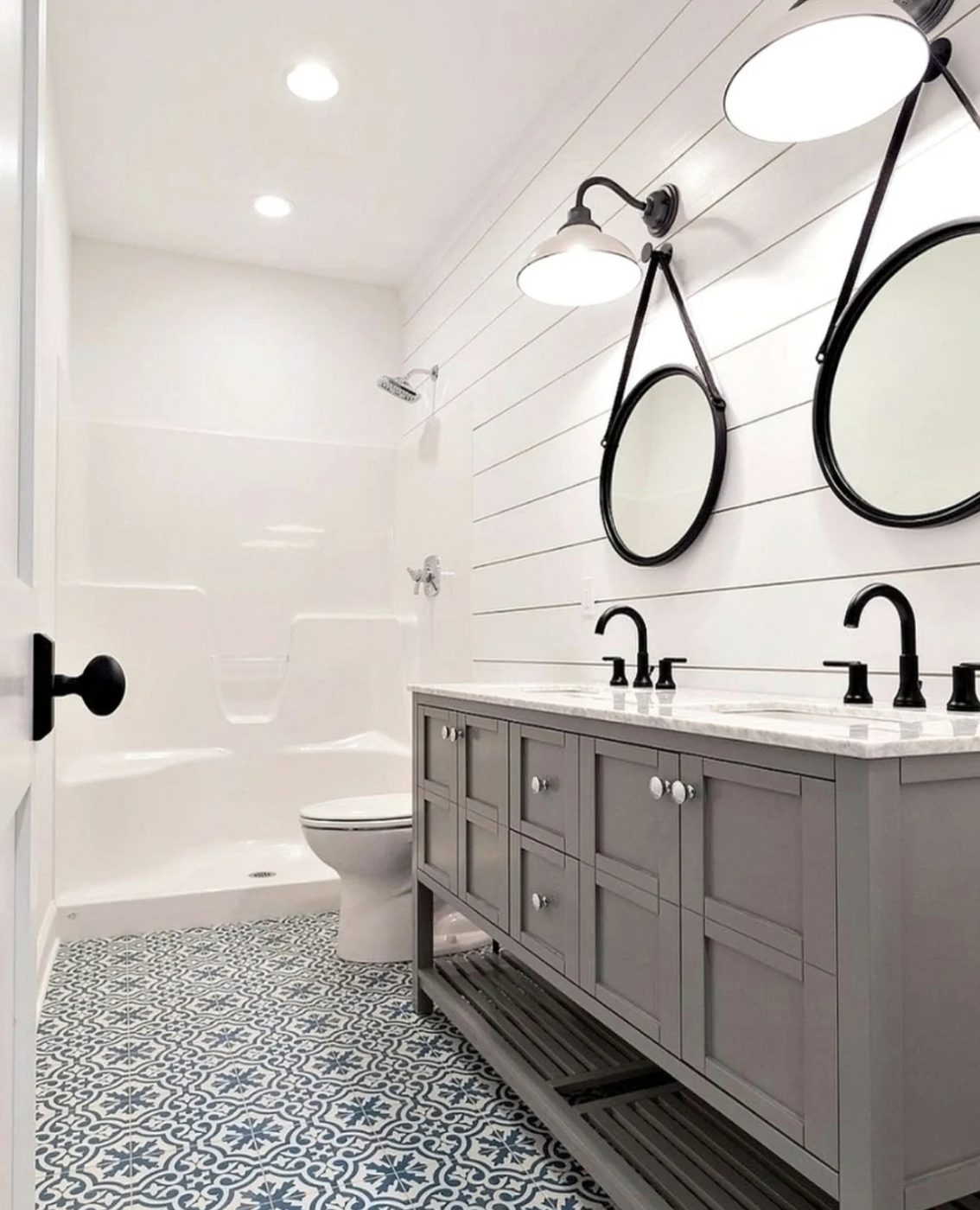 Bathroom With Horizontal Shiplap Walls And Hanging Circle Mirrors, Double Sinks, Blue And White Patterned Tile Floor