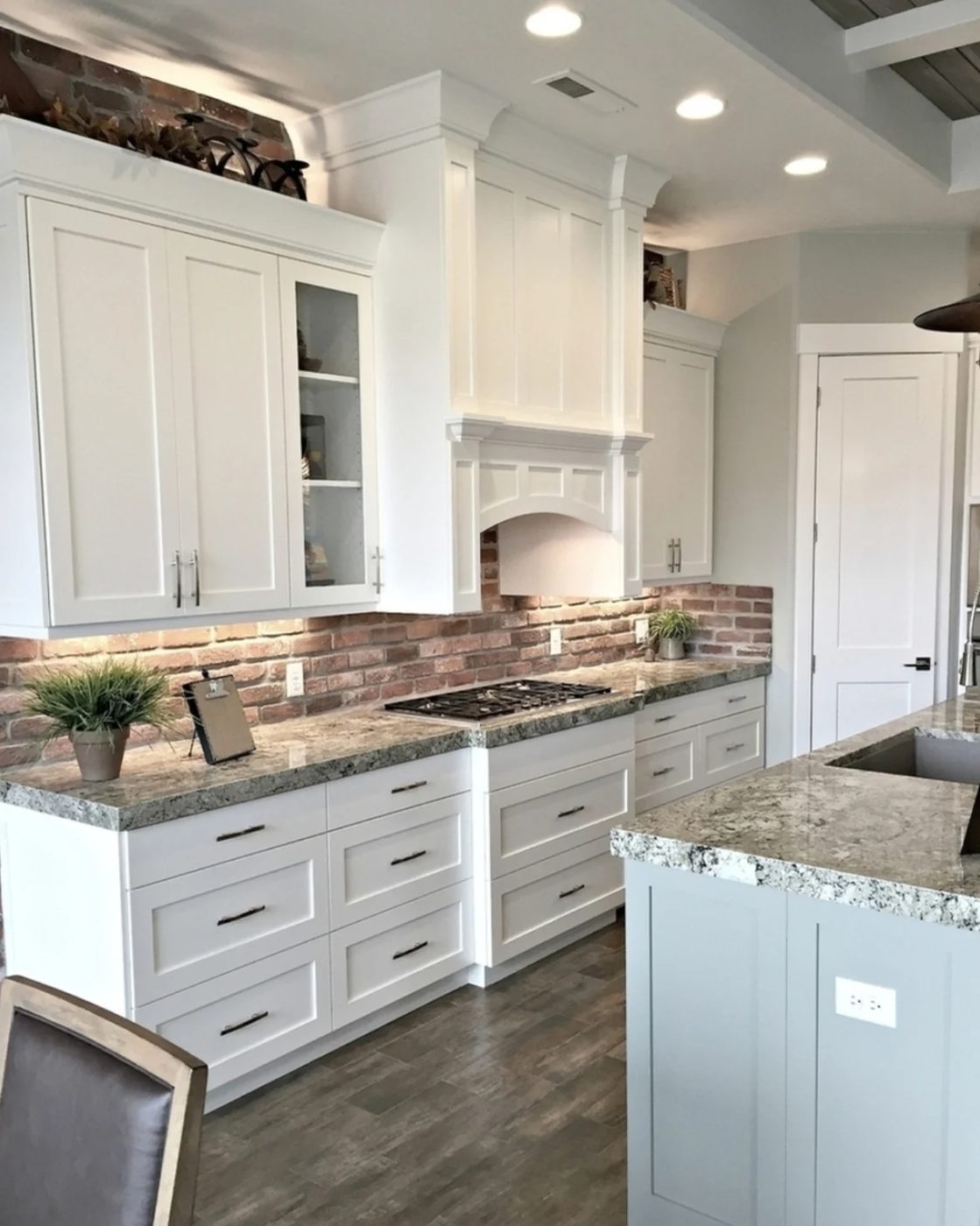Kitchen With White Cabinets, Granite Countertops, Blue Island, And Brick Backsplash