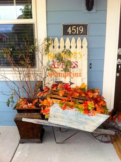 Cute Fall Porch With Wheelbarrow Full Of Fall Leaves And Fence With Fall Words