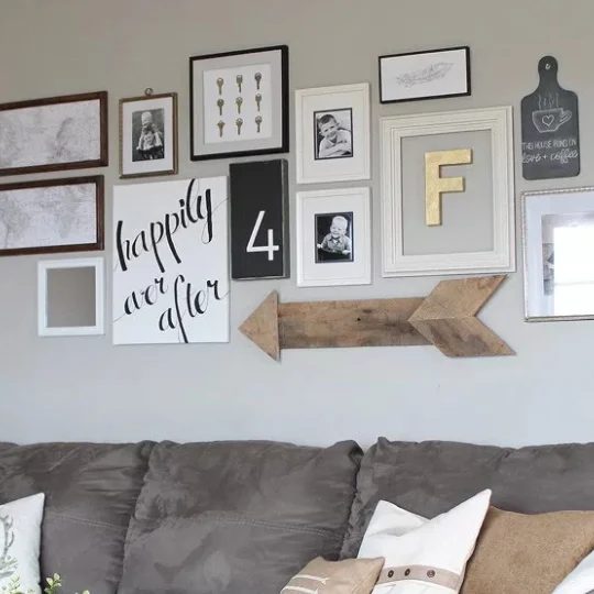 Gallery Wall Above Grey Couch With Wooden Arrow And White Frames With Black Accent