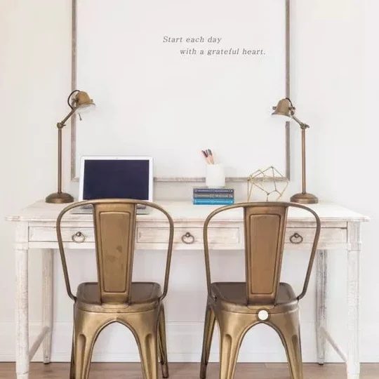Chic Neutral Homework Station With White Table, Gold Chairs And A Large White Print With Small Text