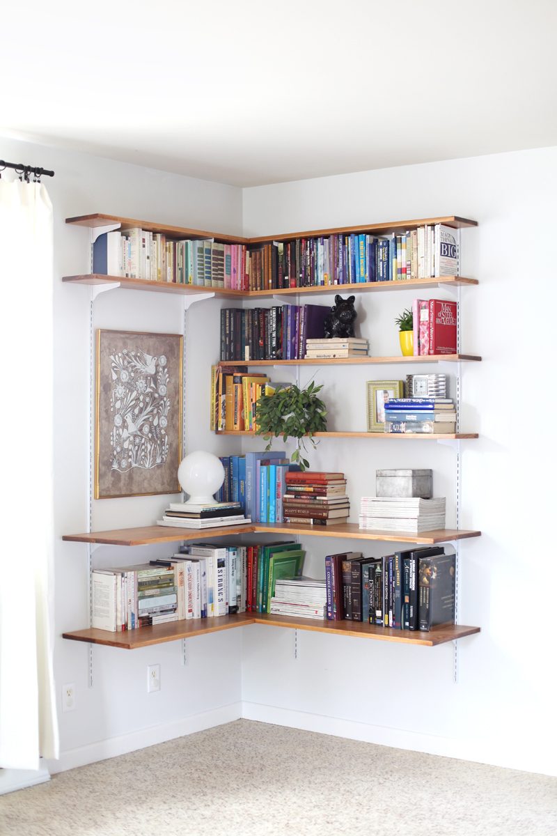 Great use of inexpensive track shelving! Use the brackets and tracks but swap in wood shelves for an industrial look, and this corner shelf looks memorable!