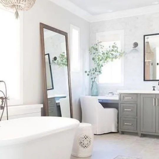 Farmhouse Bathroom With White Tub, Colored Cabinets, Leaning Wall Mirror