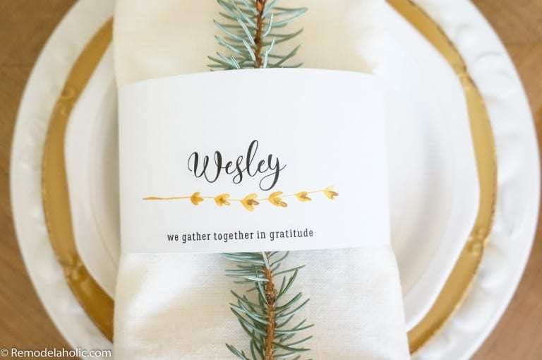 Tablescape With White And Gold Accents, White Napkin, Pine Branch, And Printed Name Card