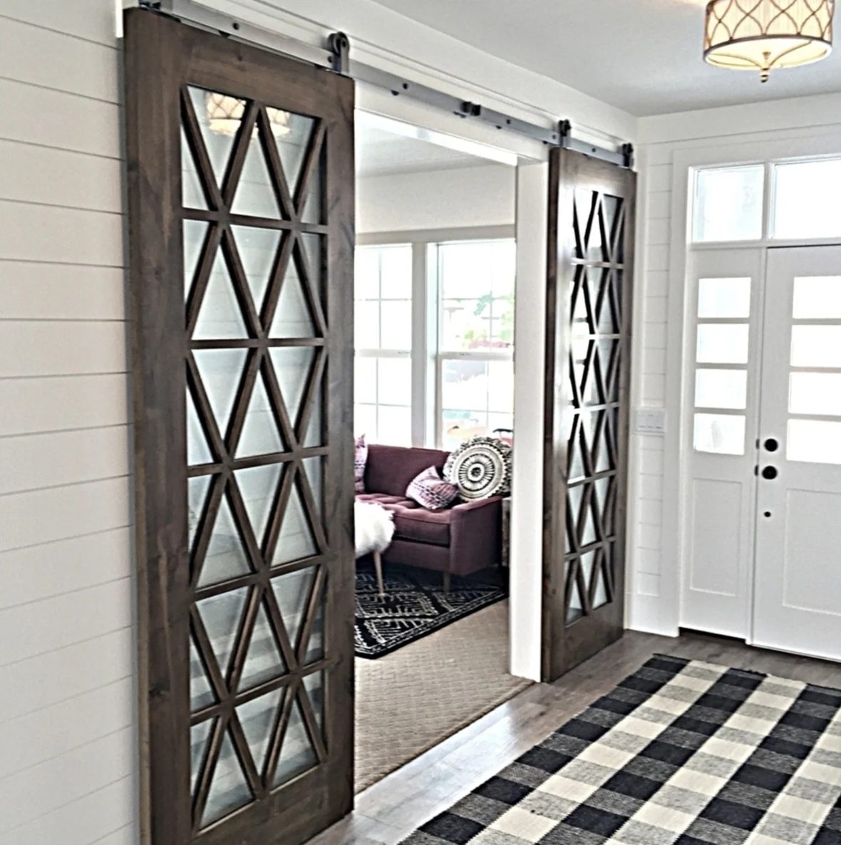 Entryway With Sliding Barn Doors To Living Room, Black And White Checkered Rug In Entry And Purple Couches Seen Through Doorway