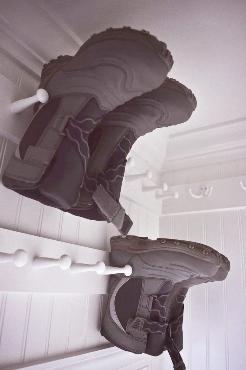 use shaker pegs to hold winter boots for off-season storage above the door in a hall closet organization project