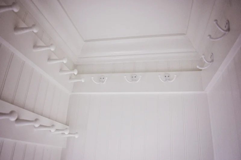 maximize hall closet storage space by organizing with hooks hung high above the door frame