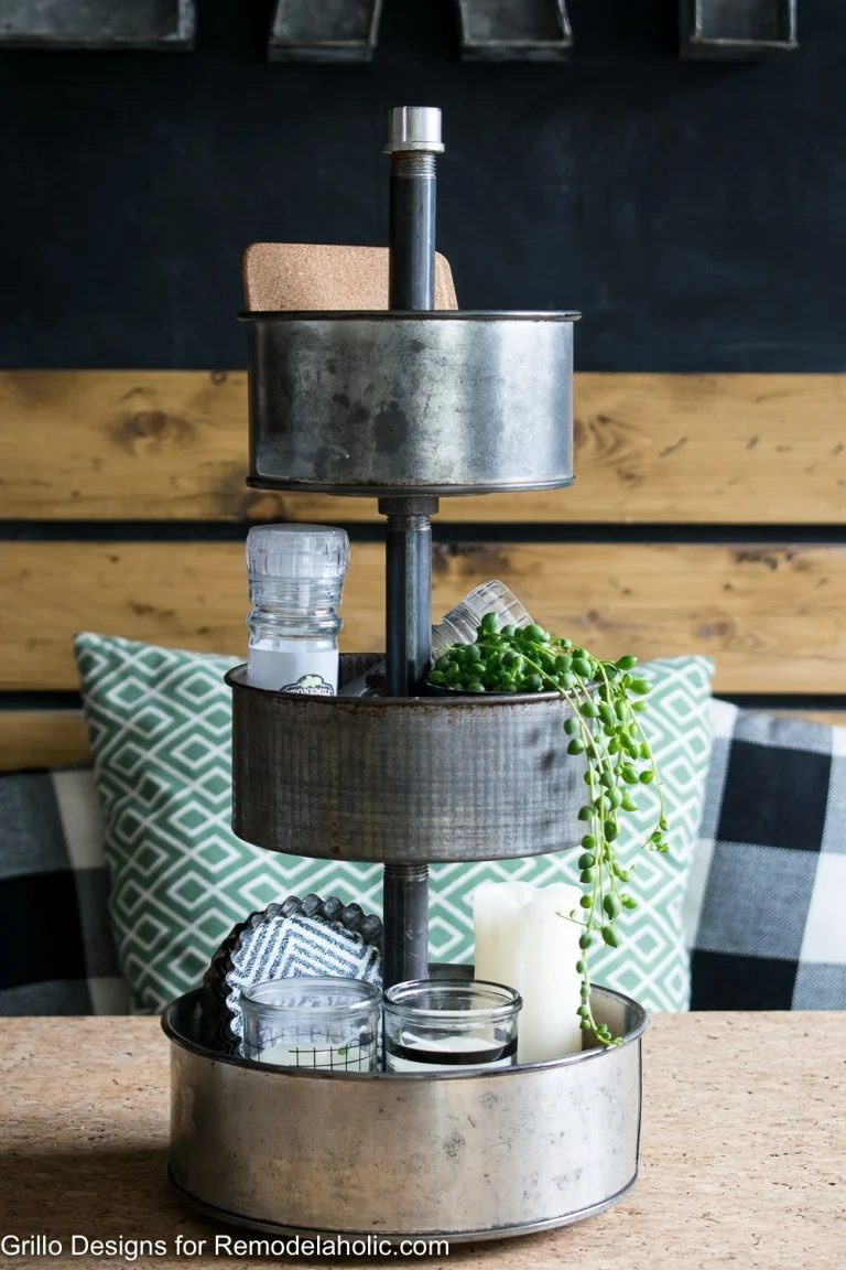 Rotating Three Tier Metal Tray Organizer On Wood Table With Salt, Candles, And Green Plant Inside