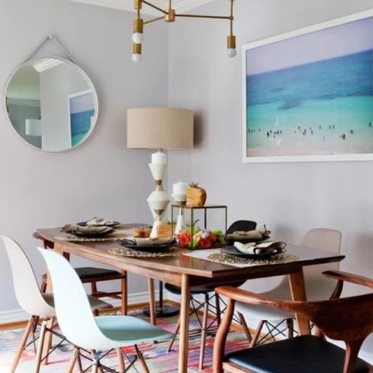 Dining Areaa With Wood Table, Circle Mirror, And Blue Painting
