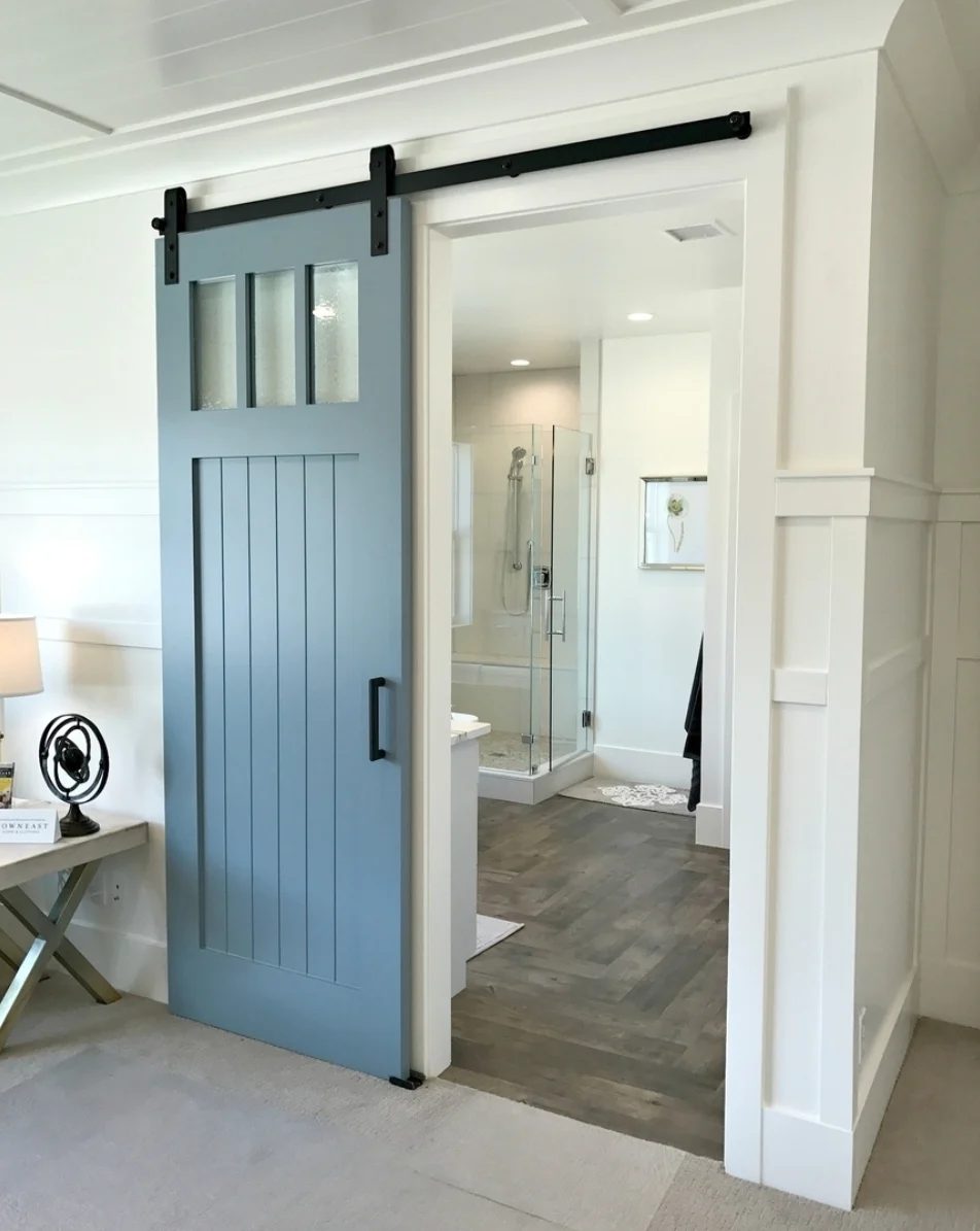 Blue Barn Door Leading Into Bathroom, White Walls, Black Handles