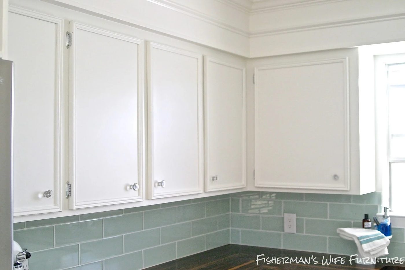 glass knobs and molding on white kitchen cabinets with glass subway tile backsplash, Fisherman's Wife Furniture featured on Bekob.com
