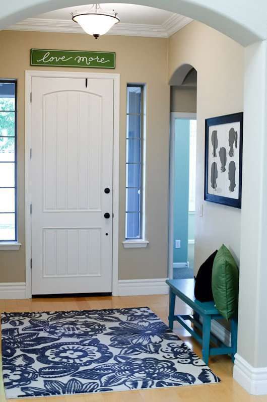 Entryway With Archway, Grey Walls, Wooden Flooring, Blue Floral Rug In Front Of White Door, Blue Bench And Love More Sign Above Door