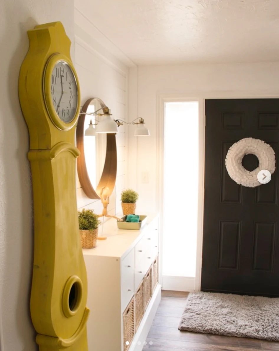 Entryway Full Of Color, Yellow Clock, Black Door, Gold Circle Mirror, White Drawers With Wicker Baskets